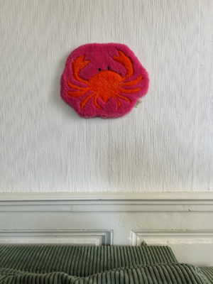 Tapis mural en forme de crabe réalisé en tufting, avec des finitions sculptées et une attache en métal noir. Cette décoration crabe unique apporte une touche contemporaine et chaleureuse à l'intérieur.